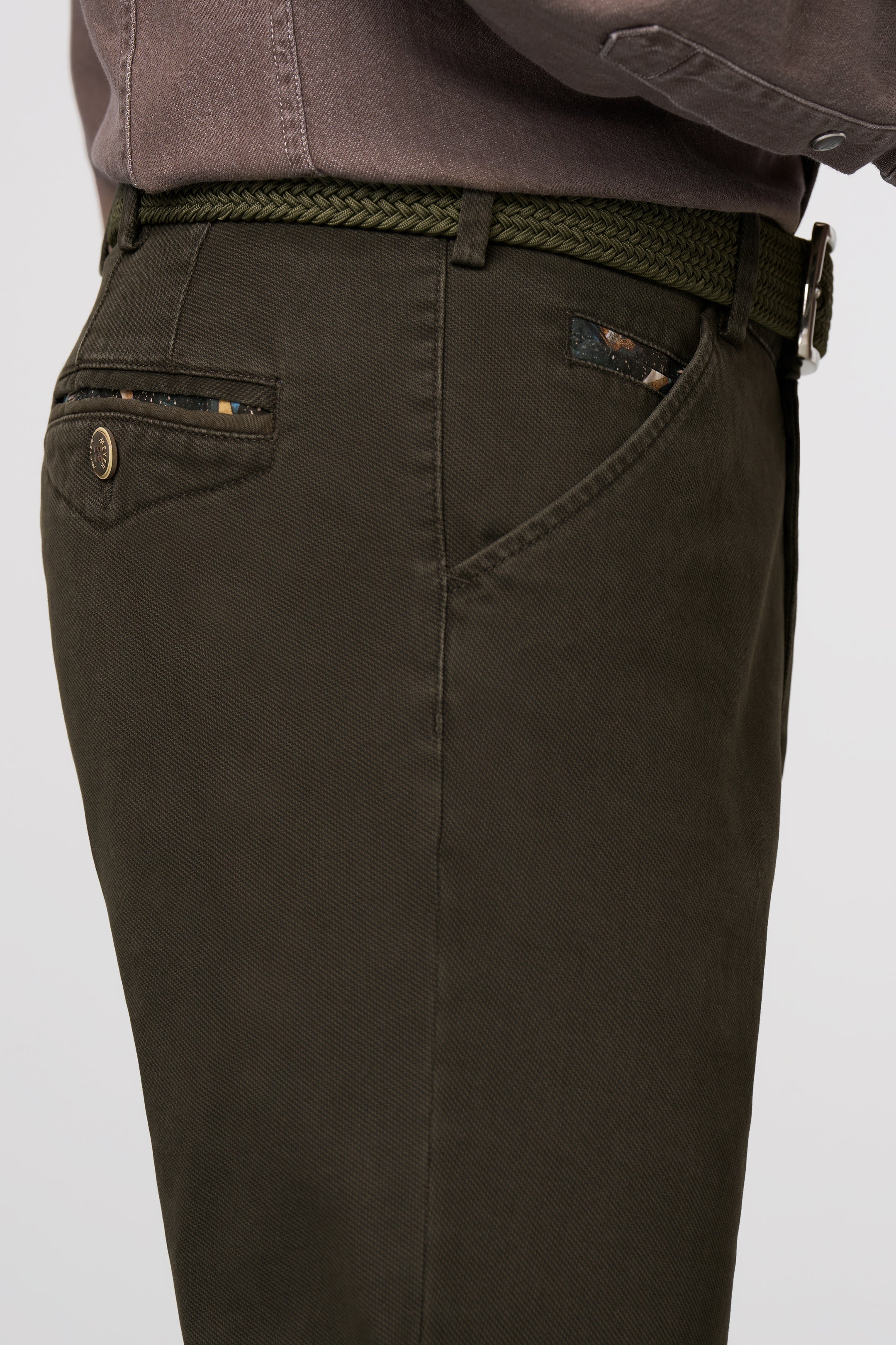 Dark green pants with a belt on a light gray background